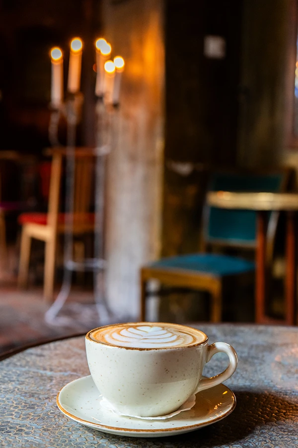 Cappuccino op tafel bij Eszeweria met kaarslicht op de achtergrond